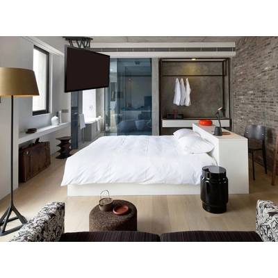 Modern hotel room with a central double bed, wall-mounted flat-screen television, and an open bathroom wall.