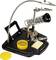 Soldering aid with crocodile clips, magnifying glass, soldering iron stand, sponge and cleaning pad on a black stand. For precise soldering work.