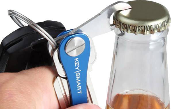 Someone opens a bottle with a bottle opener attached to a blue keyring.