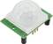 A PIR motion sensor on a green circuit board with a white dome cover and connector pins for motion detection.