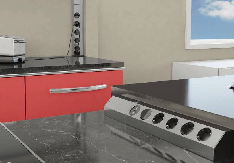 Modern kitchen with a black worktop, red cupboard and power strip. Window with blue sky in the background.