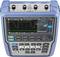 Portable digital oscilloscope with a colour display, showing voltage waveform and measurement parameters. Buttons and connectors are visible.