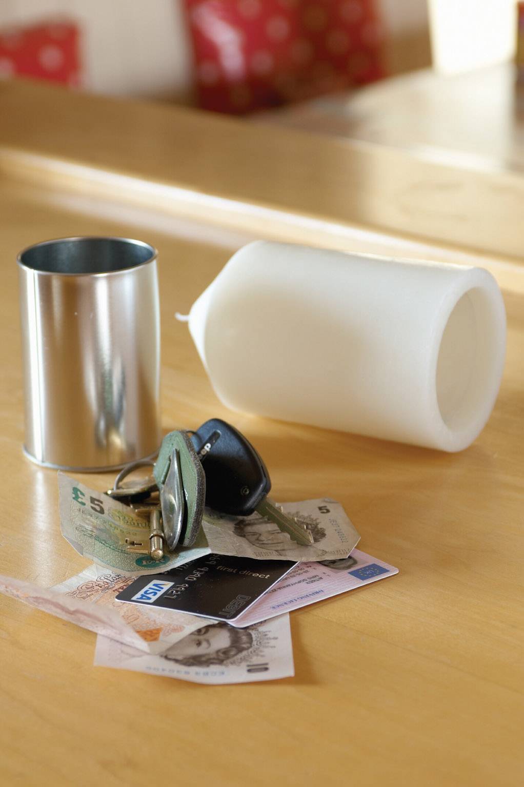 On a table lie a candlestick, a white candle, banknotes and keys.
