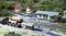 Model railway scene with a station building, track, wooden wagons, several small houses and figures in a rural setting.
