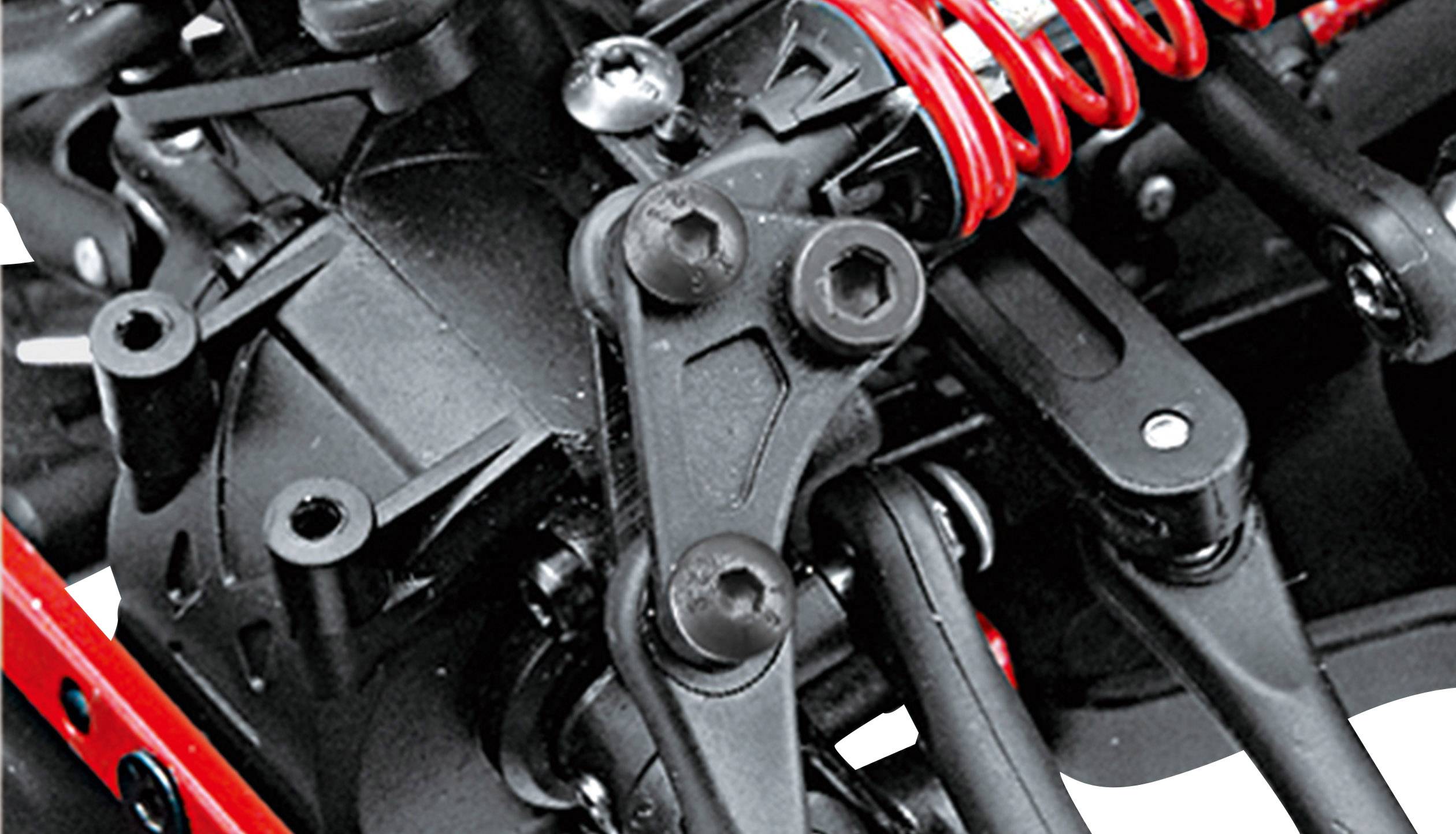 Close-up of a black mechanical device with red spiral springs and metallic components, possibly part of a vehicle.