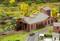 Miniature steam locomotive in a model railway depot with sliding doors. Landscape in the background with trees and roads.