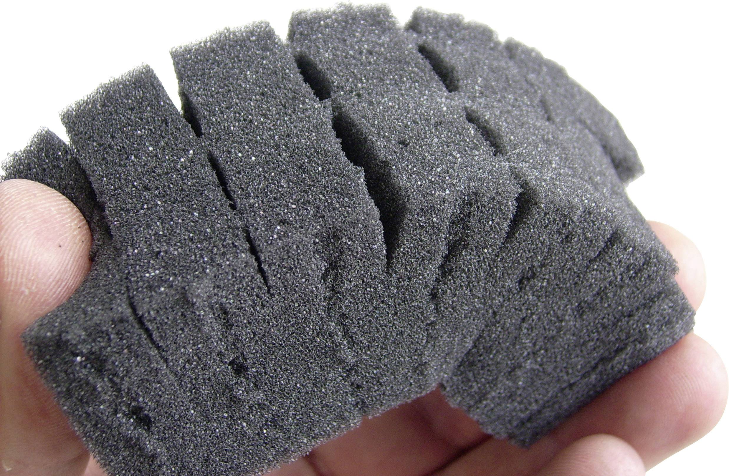 A dark grey, textured sponge is being held in the hand, likely for cleaning or polishing purposes.