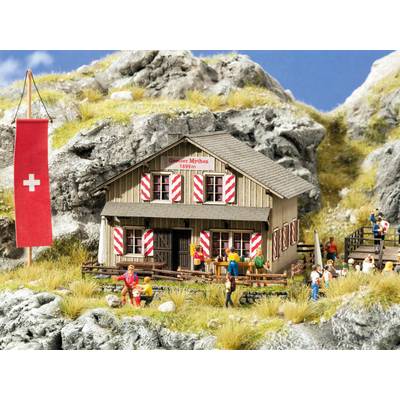 A miniature model depicts a mountain hut with a Swiss flag, surrounded by figurines and a rocky landscape.