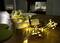 A laid table with a wine glass and a glowing string of lights wrapped around a napkin. Atmospherically lit.