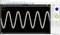 An oscilloscope display shows two sinusoidal waves on a diagram; the waves are phase signals in different colours.