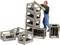 A man in workwear is stacking metal crates. Some crates are lying nearby.
