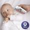 A baby is lying on a bed while a hand uses a digital ear thermometer, displaying a temperature of 37.0°C.