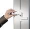 A hand opens a white safety lock on a white door, demonstrating the functionality of a locking system.