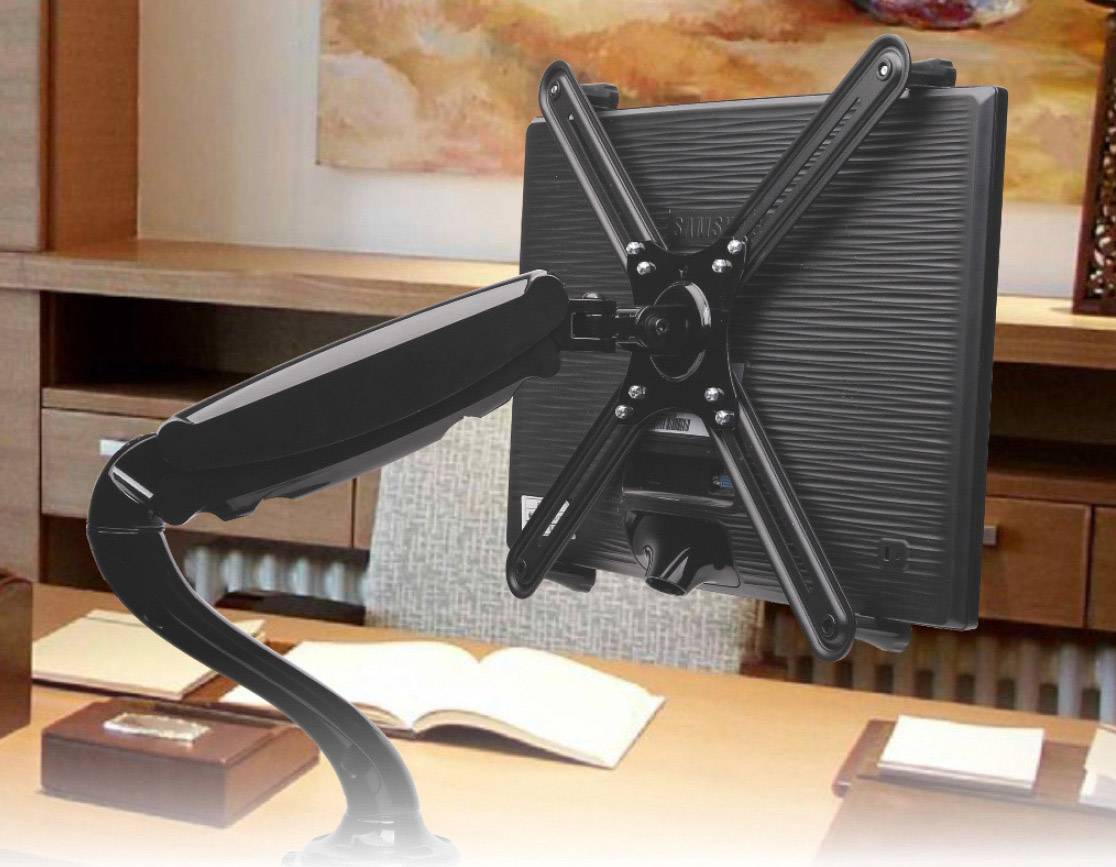 A monitor mount with a flexible arm is mounted on a desk, surrounded by office items such as an open book.