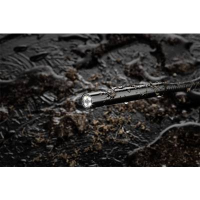 A black hose in close-up, lying in muddy ground, with bright light at its tip.