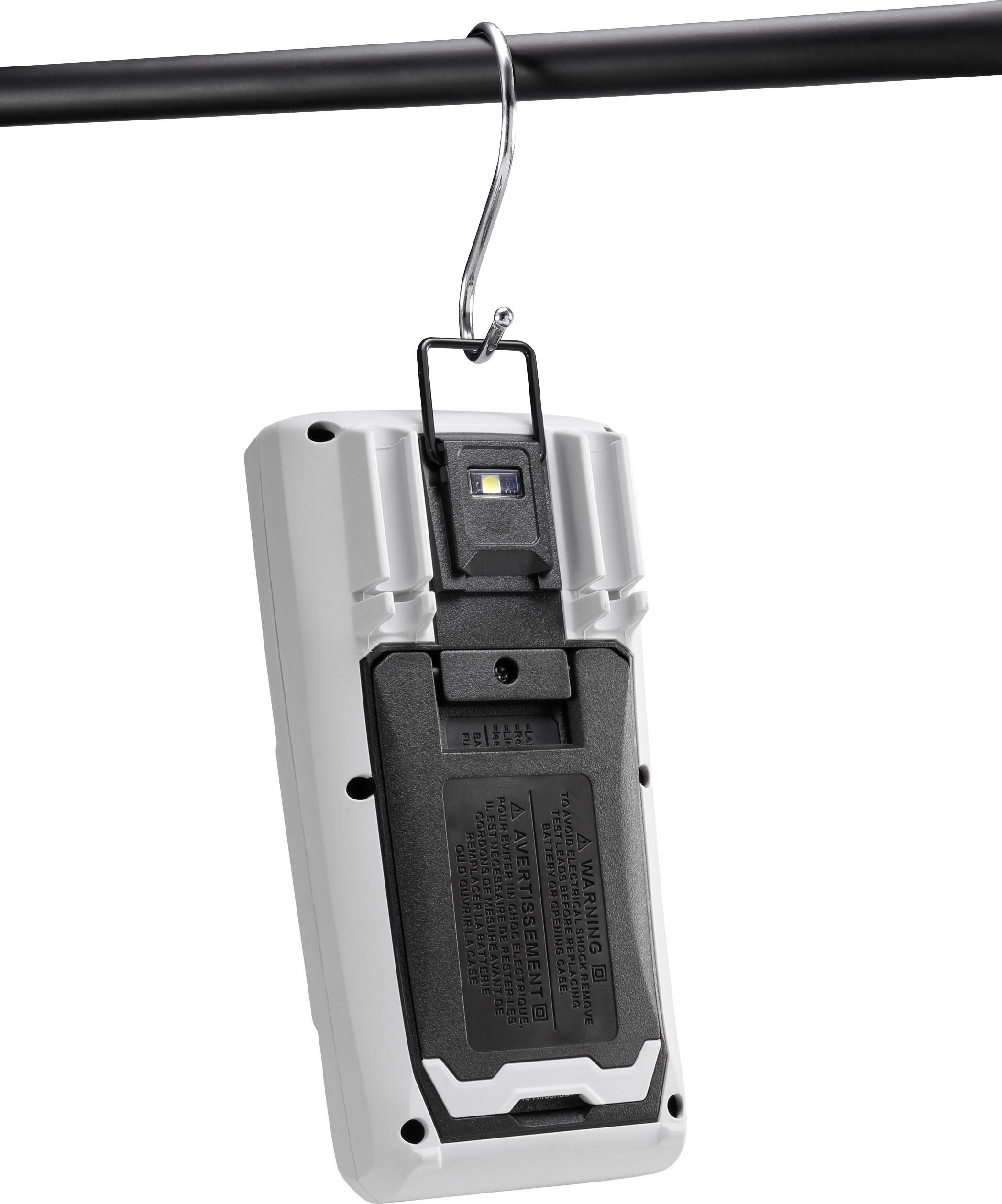 A portable, white device with hooks is hung on a pole. It has a small screen and buttons on the front.