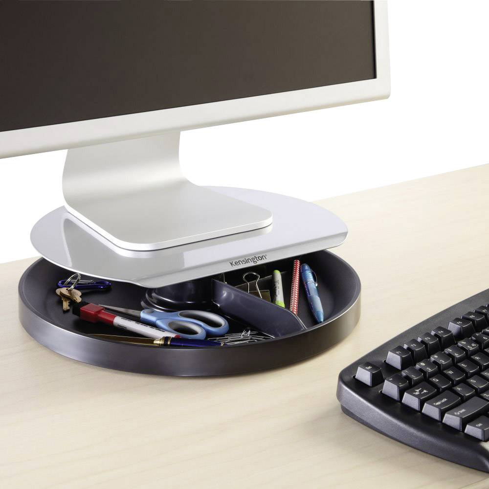 A monitor sits on a round shelf with compartments containing pens and office supplies. A keyboard lies beside it.