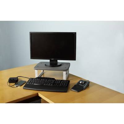 'A computer workstation with a monitor on a stand, keyboard, trackball and smartphone, connected by a charging cable.'