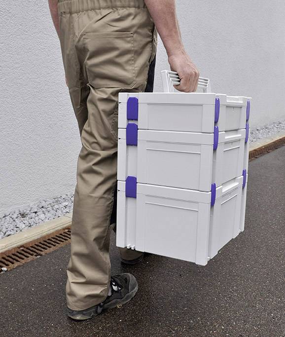 A person is carrying two stacked boxes along a path.