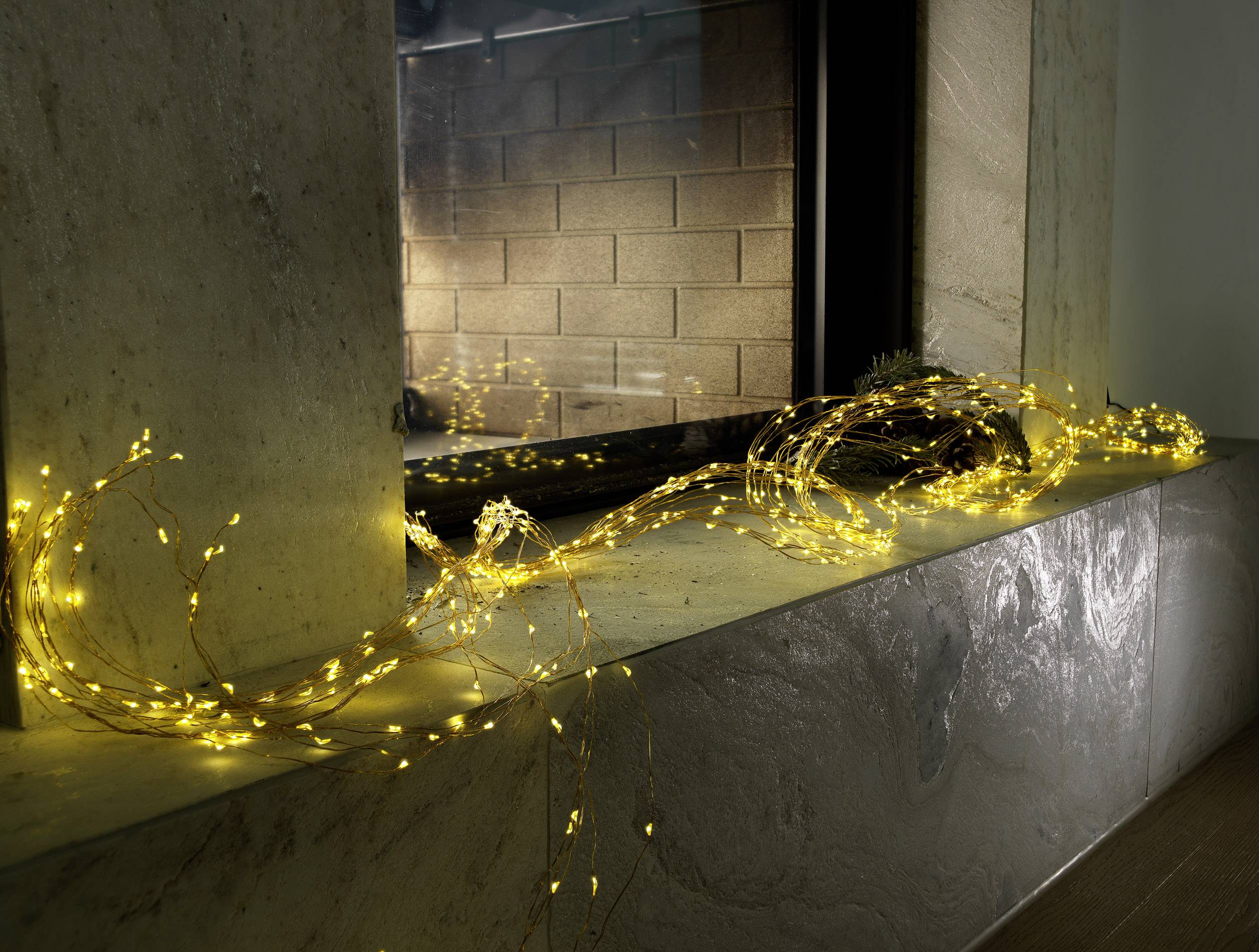 Yellow fairy lights lie decoratively on a stone windowsill, gently illuminating the room and creating a cosy atmosphere.