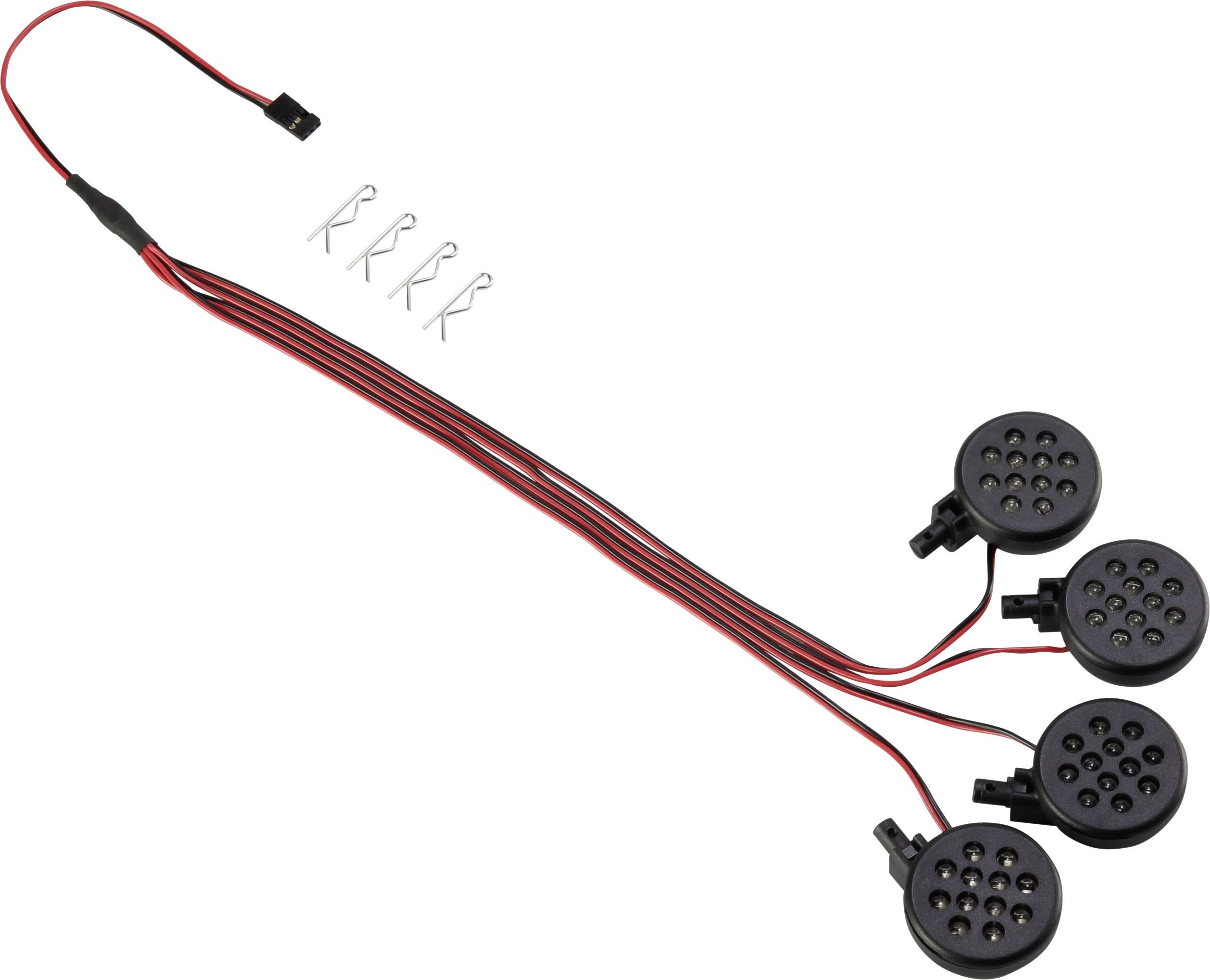 Four black speaker capsules, connected by red and black wires, lie on a white surface. Small metal clips above.