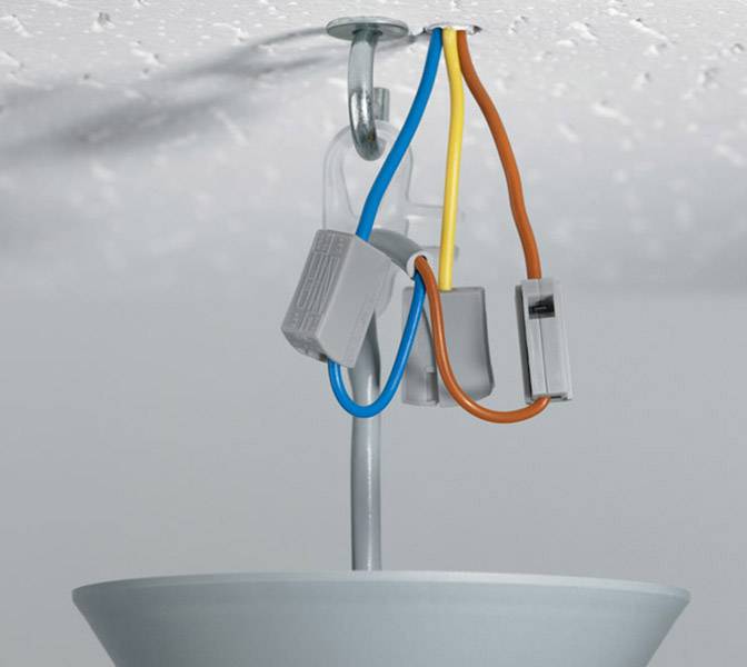 A ceiling light with exposed, coloured wires (blue, yellow, orange) hangs from a hook fixture on a white ceiling.