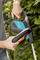 A man is cutting a hedge with a Gardena electric hedge trimmer.