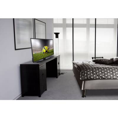 Flat-screen TV in a modern bedroom showing a football match. Bright windows in the background, pictures on the wall to the left.
