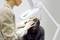 A person is examining the scalp of a seated man using an illuminated magnifying glass, possibly during a medical examination.