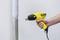 A person is holding a yellow hot air blower against a vertical pipe to heat and shape the coating.