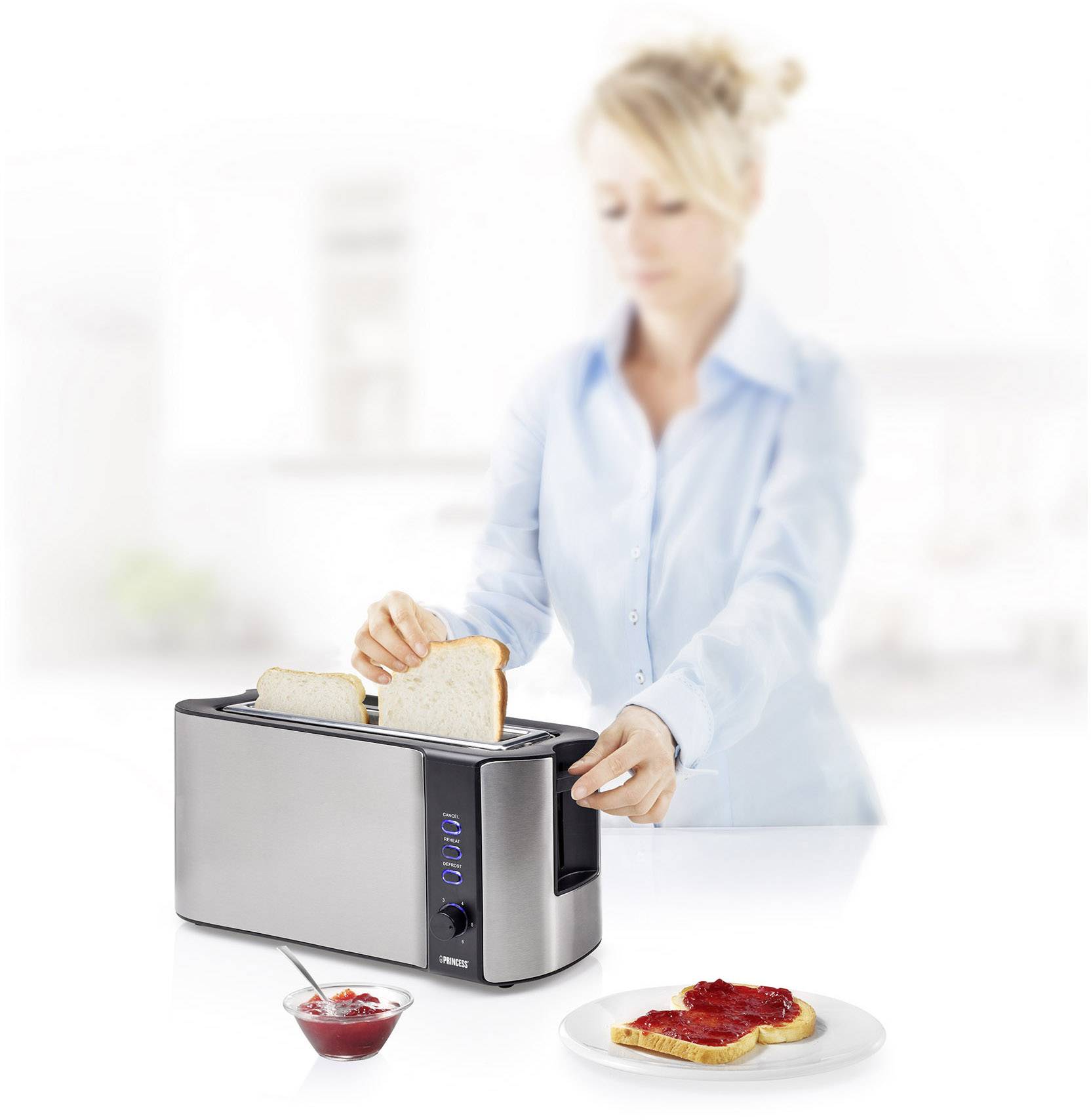 A woman toasts bread in a modern toaster; a plate with toast and jam sits beside it.