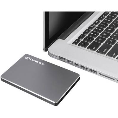 External hard drive next to an open laptop on a desk. The laptop is partially visible.