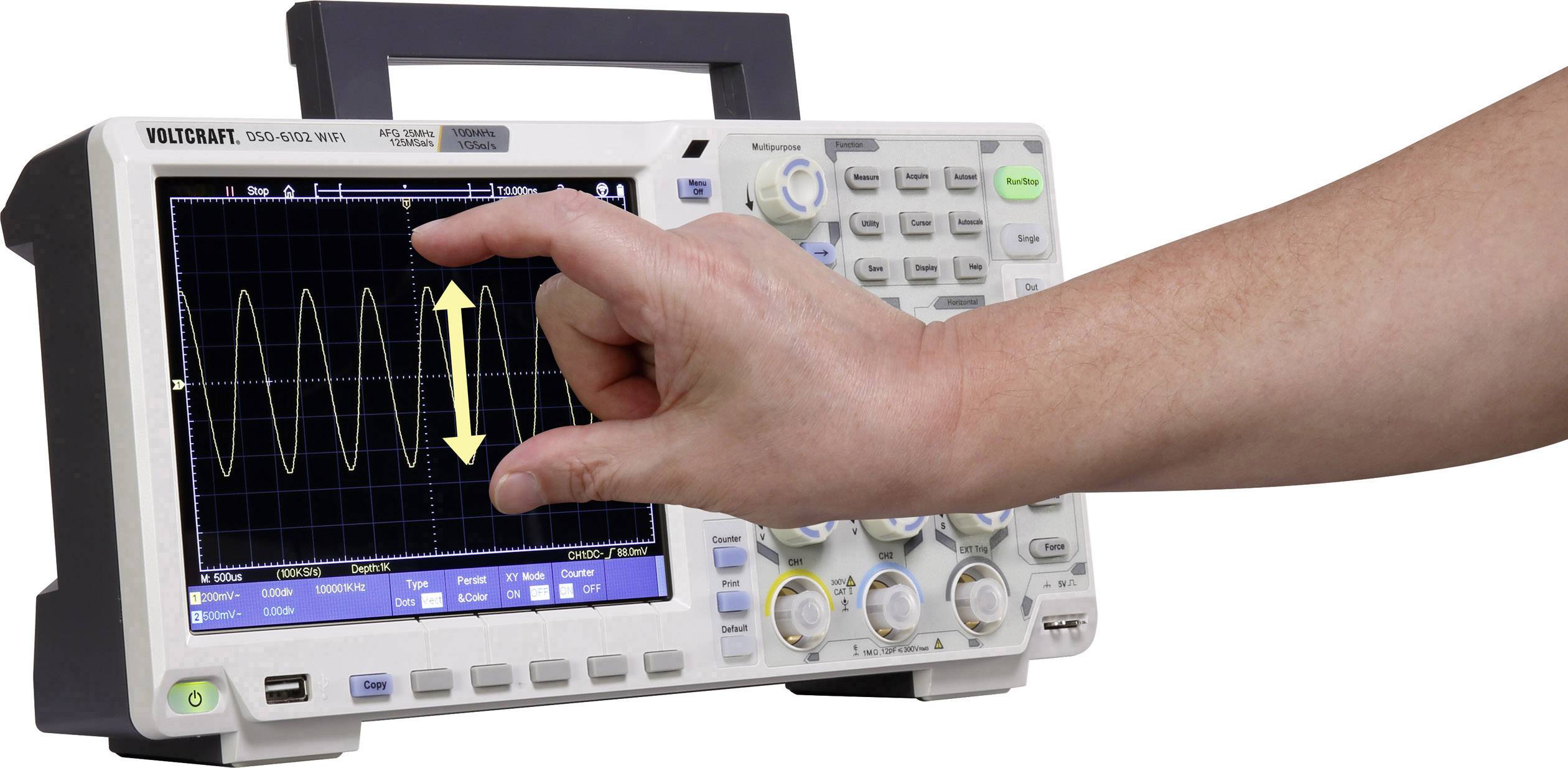 A oscilloscope with a hand pointing to the display. The display shows a wave-like curve with a vertical double-arrow.