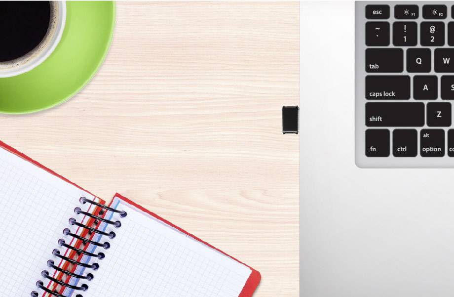 On a wooden table lies an open, squared notebook and a cup of coffee. A portion of a laptop keyboard is visible in the top right corner.