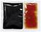 Two rectangular, sealed sauce sachets side by side. On the left, a black sauce, on the right, a reddish-brown sauce.