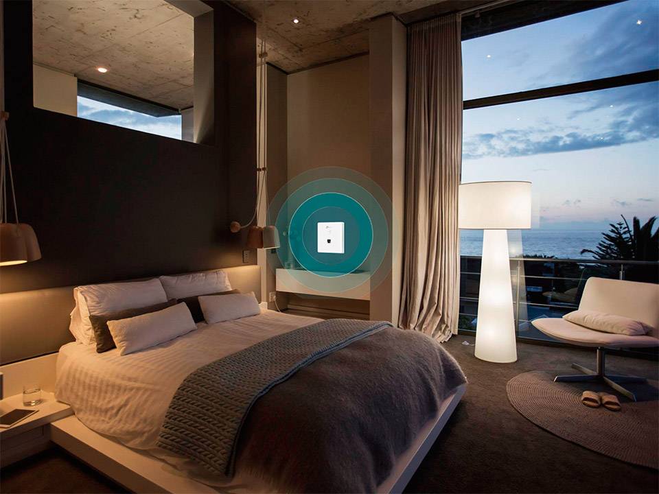 A modern bedroom with a large bed and lamp, offering a view of the ocean through a window. The room feels calming and luxurious.