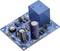 A blue electronic circuit board with multiple components, including capacitors, resistors, and a blue relay cube.