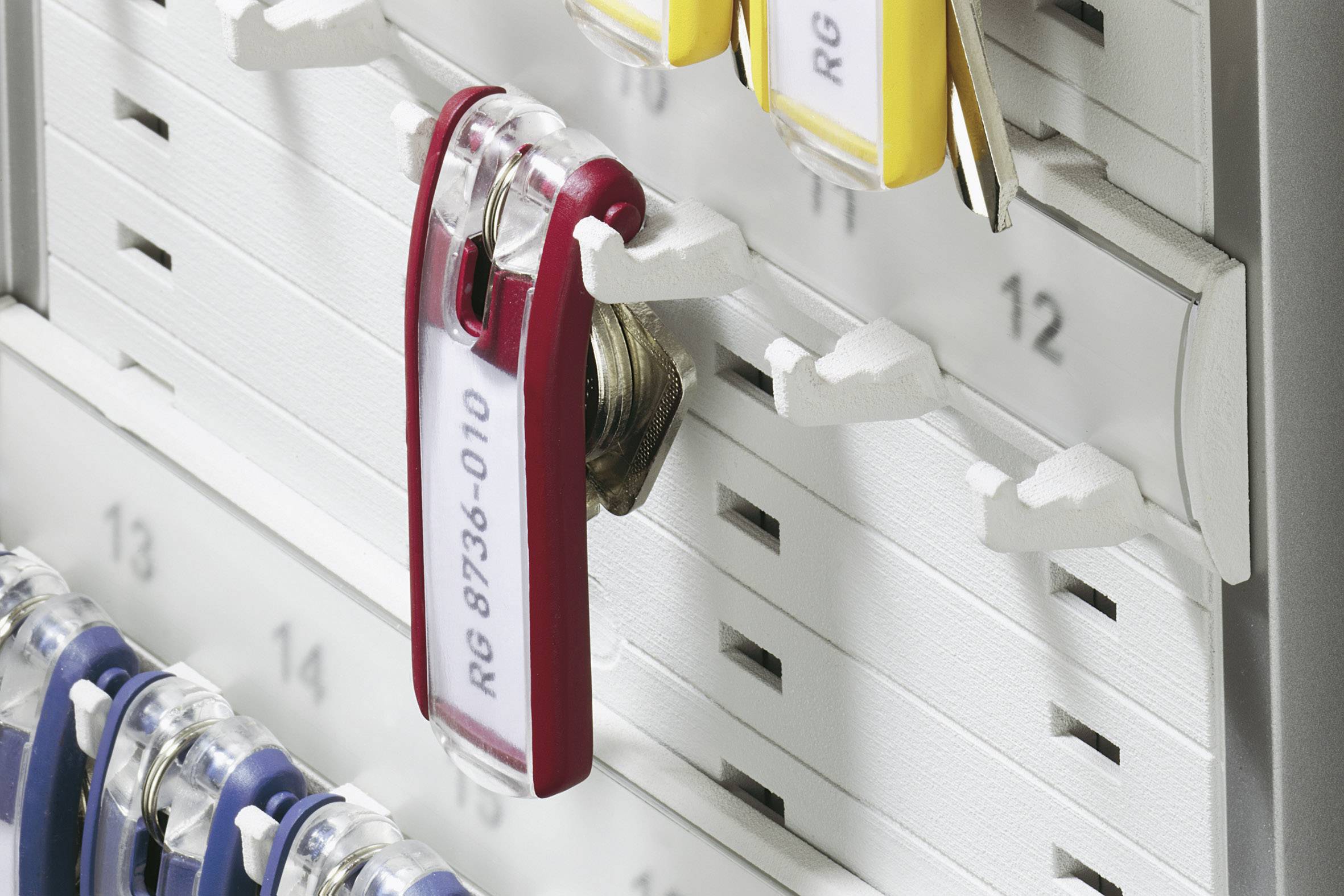 Several labelled key tags hang in an orderly manner on a numbered board. A red tag with 'RG 8736-010' is in the foreground.