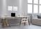 Modern desk with a laptop, lamp, and chair, with a sofa beside it. Bright walls and large windows allow plenty of daylight to enter.