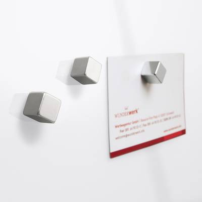 Two silver magnets on a white background, one holding a white card with a red border and text reading 'WUNDERwerk'.