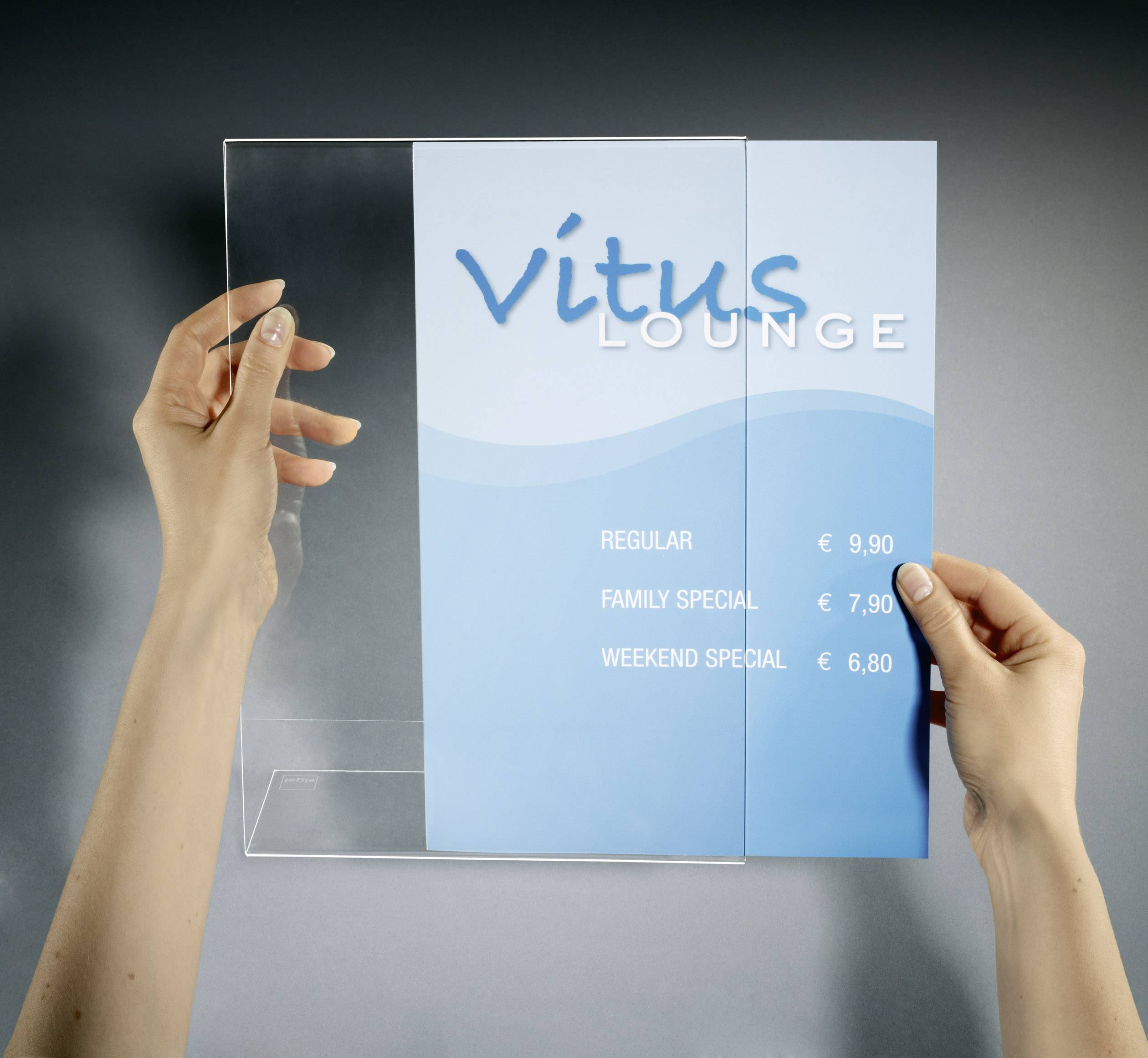 Two hands are holding a transparent sign holder with a blue poster displaying the 'Vitus Lounge' and prices for offers.