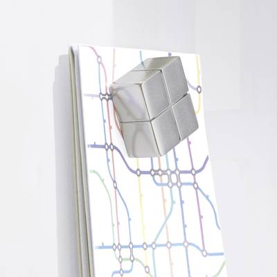 A silver cube placed on a notebook with a colourful underground map; demonstrates modern design and organisation.