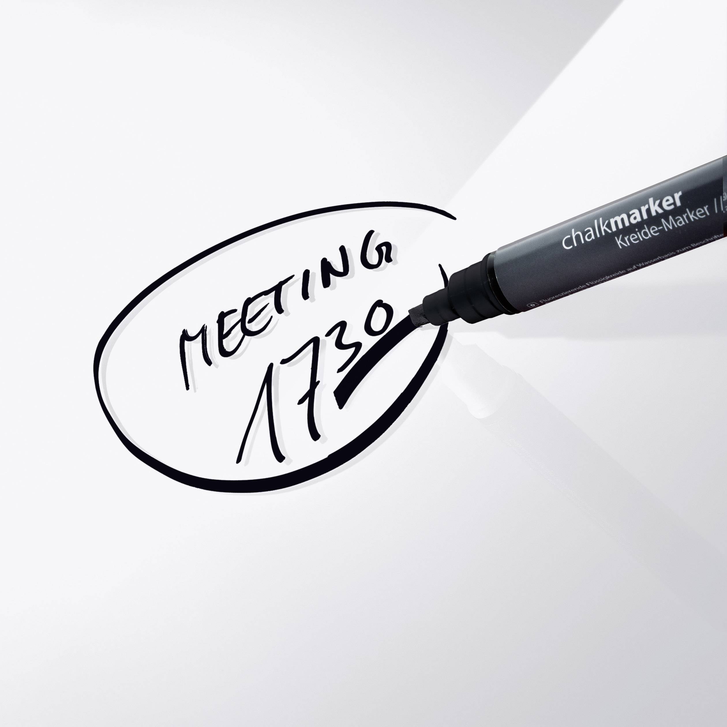 A chalk pencil writes on a white board 'Meeting 17:30'.