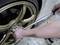A person is tightening the wheel nuts of a golden car tyre using a torque wrench.