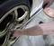A person is tightening the wheel nuts of a car with a torque wrench.