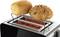 A toaster with two bread rolls, one plain and the other covered in seeds, sits on a bread rack above the glowing red heating elements.