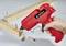 A hand holds a red hot glue gun while wooden dowels are being inserted into wooden pieces, likely for furniture assembly.