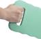 A hand is holding a green knee cushion with a handle. The cushion has a textured surface and wavy edges.