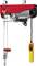 Electric winch with a red housing and yellow remote control; used for lifting heavy loads in workshops or garages.