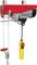Electric winch with a red housing and yellow control switch, designed for lifting heavy loads in industrial environments.